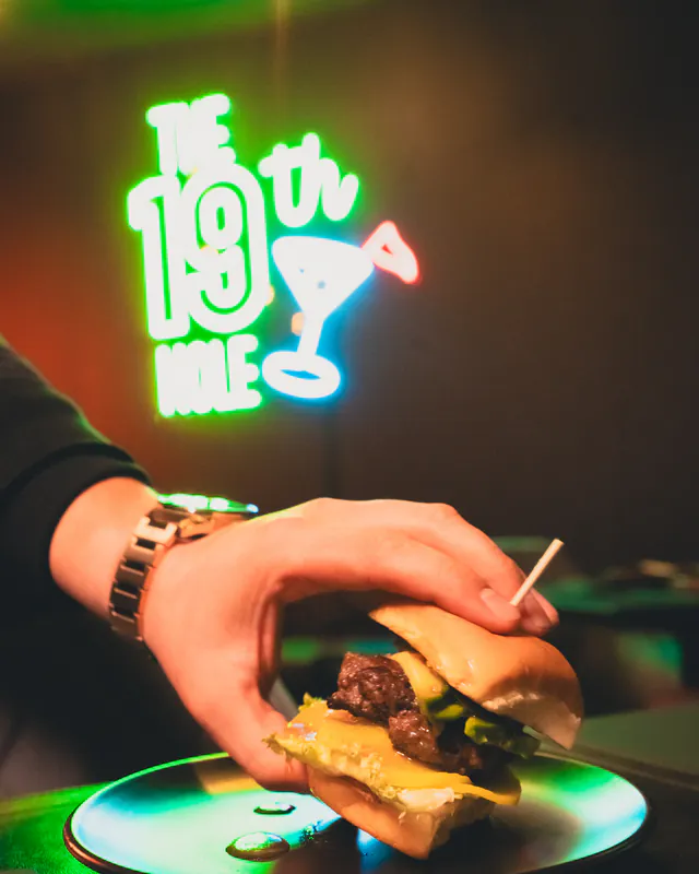 Sándwich de carne bajo el letrero de neón «The 19th Hole»