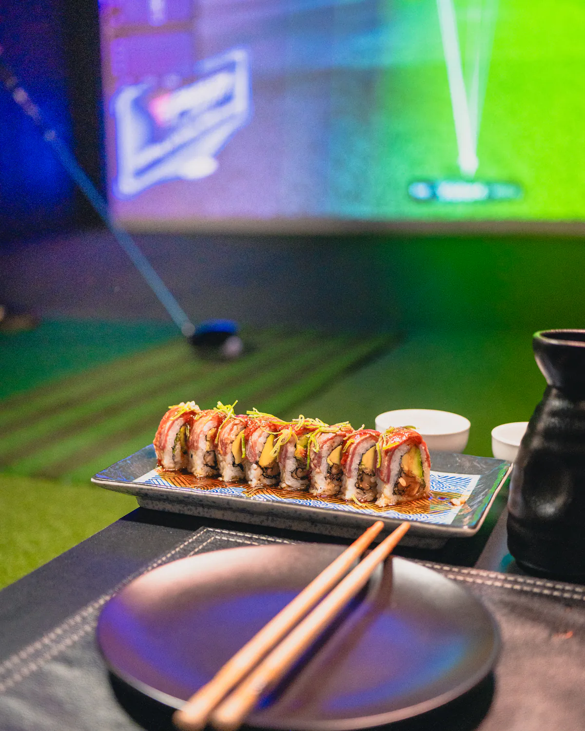 Roll de sushi en la mesa, con el simulador de golf al fondo